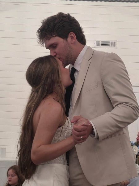 A close-up, intimate capture of a bride and groom during their first dance at their wedding venue, with the groom kissing the bride's forehead.